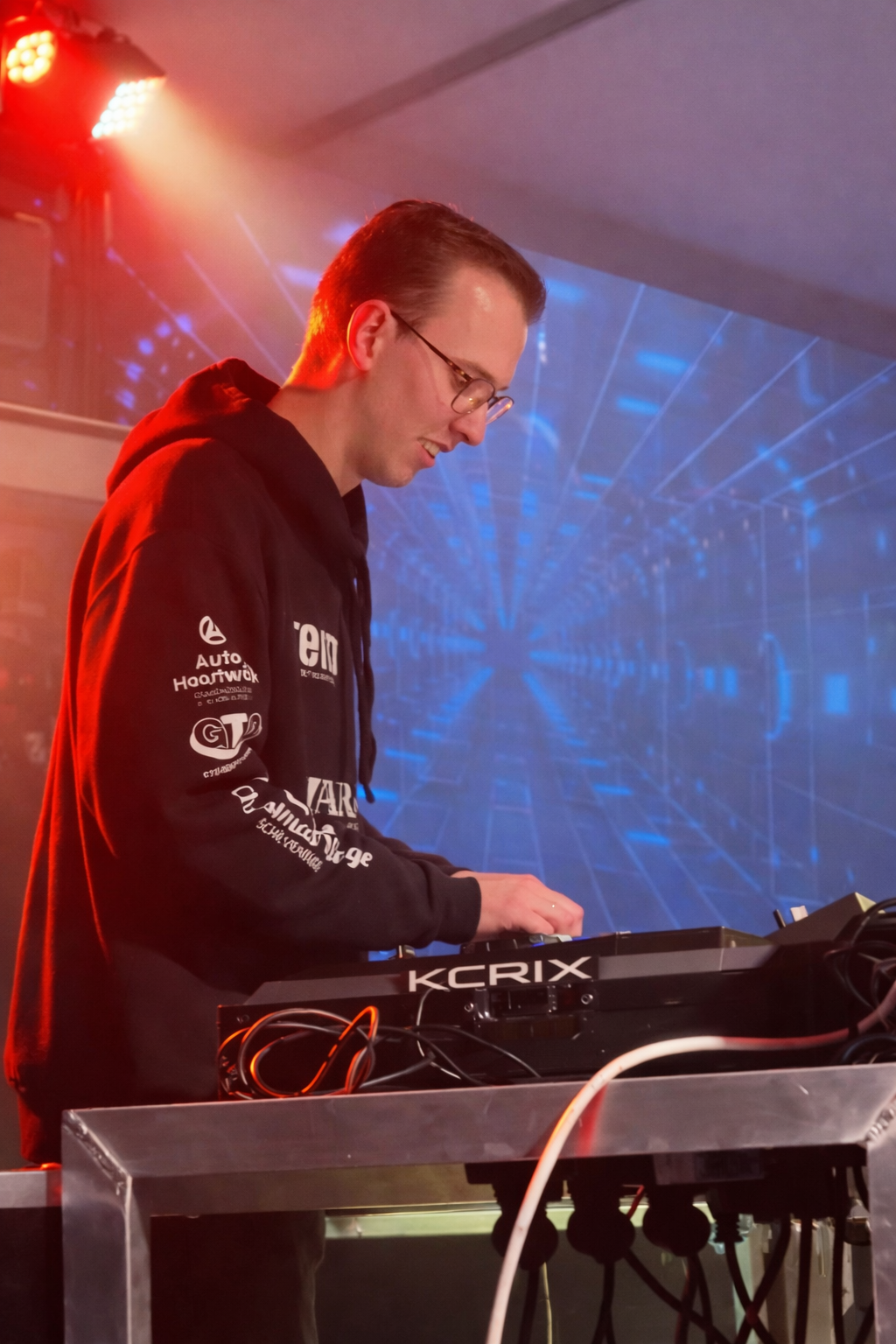 DJ KCRIX tijdens een optreden met rood en blauw licht